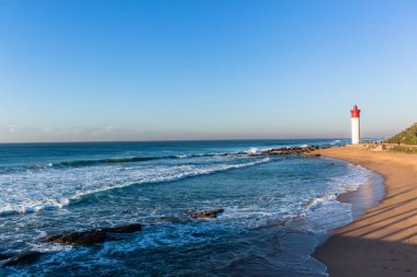 Bir tatil yaşam tarzı manzara mavi okyanus horizon ile plaj deniz feneri kırmızı beyaz yapısı closeup dalgalar.