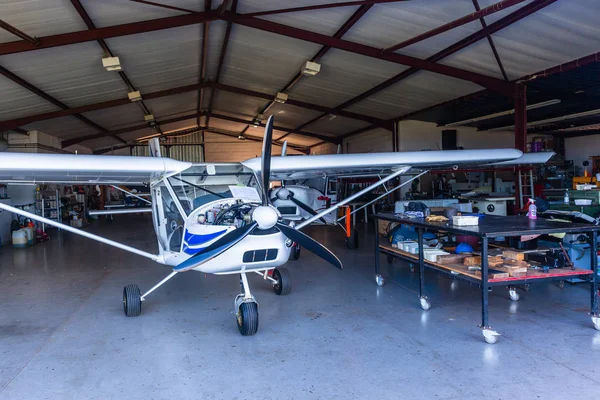 Small single prop engine aircrafts planes parked inside workshop hangar for servicing.