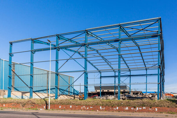 Warehouse factory steel frame structure beams girders exposed to blue sky renovations in progress.