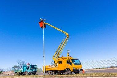 Kamyon araç bakım onarım Polonyalılar ışık ampul mavi gökyüzünde yapıyor genişletilmiş hidrolik kol kova içinde yüksek rütbeli elektrikçi.