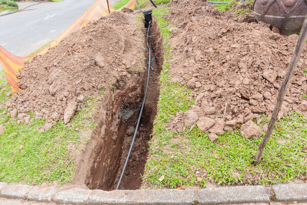 Новые высокоскоростные оптоволоконные кабели интернета установлены под землей в траншеях вдоль дороги перед жилыми домами
 .