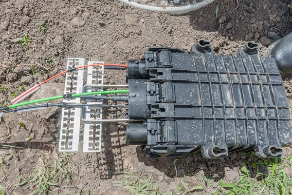 Communications construction of new internet fast speed fiber optic cables been installed underground by technicians in connection water proof cases and inserted box along road of residential homes .
