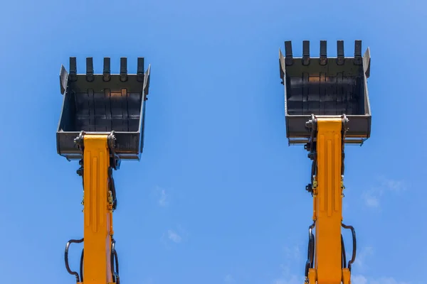 Grävmaskiner två hink skopor blå himmel — Stockfoto