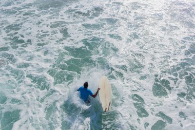 Surfer sörf tahtası atlar kapalı plaj iskele iskele Okyanusu ile su altında sörf dalgalar için hızlı bir giriş için bir closeup arka arka eylem aşağıya doğru fotoğraf.