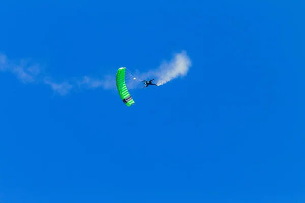 Fallskärmshoppare fallskärmshoppning grön fallskärm flygning blå himmel — Stockfoto