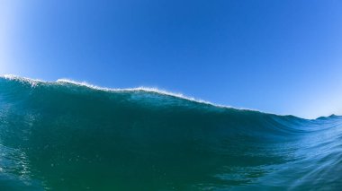 Okyanus dalgası yüzmeyle karşılaşır. Mavi su duvarının yakın çekim fotoğrafı sahil şeridine doğru çökmek üzere..