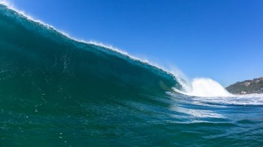 Okyanus dalgası yüzerek kıyıya vuran mavi suyun yakın çekim sularıyla karşılaşır..