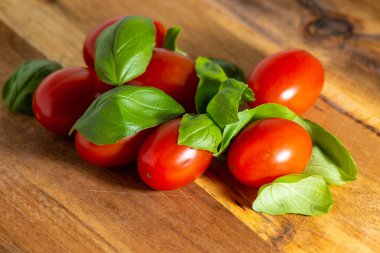 Kırmızı domates fesleğen ile kesme tahtası üzerinde ahşap backgr yaprakları