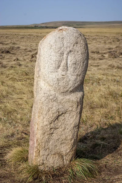 a stone idol stands in the steppe