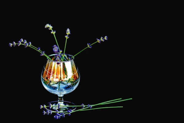 Flores de lavanda en un vaso de vidrio transparente sobre un fondo negro. Enfoque selectivo. Copiar espacio . — Foto de Stock