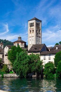 San Giulio Kilisesi 'nin çan kulesi mavi gökyüzü olan evlerin çatısından yükseliyor. San Giulio Adası, Orta Gölü