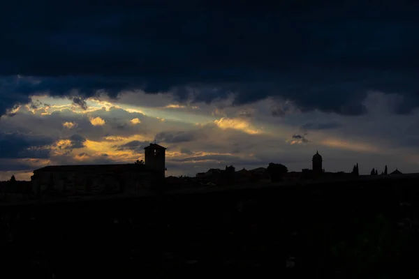 Günbatımında ortaçağ şehrinin ufuk çizgisi. Bulutların arkasından ve kiliselerin arkasından süzülen güneş ışığı binaların siluetlerini görmenizi sağlar.