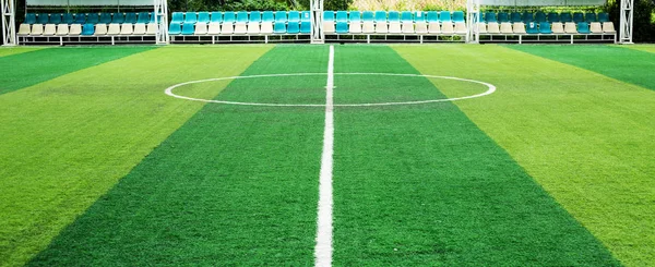 Green artificial grass football field. Half line in the middle of the football field. View from the side field.