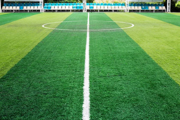 Green artificial grass football field. Half line in the middle of the football field. View from the side field.