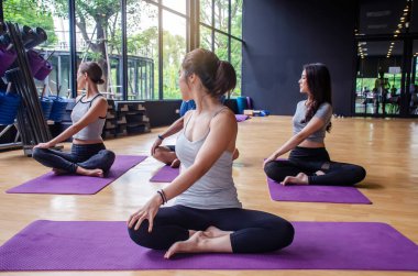 Bir grup genç sportif ve çekici insan yoga dersleri alıyor. Eğitmenle temel pozlar veriyorlar. Kapalı alanda, stüdyoda çalışıyorlar. Refah, spor ve sağlık hizmeti kavramı