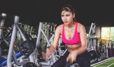 Savaş halatıyla spor salonunda egzersiz yapan genç bir kadın spor salonunda spor ipini sıhhat için kesiyor..