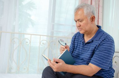 Elinde büyüteçle yaşlı bir adamın portresi evde kanepede otururken kitap okumaktır.