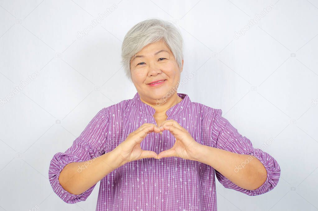 love and old people concept -  Happy senior woman showing hand heart gesture and smiling, take care of the health, or being in love