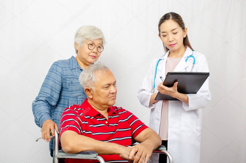 Asian woman Doctor talking to senior couple in wheelchair at hospital. Beautiful asian doctor taking care of patient in wheelchair, healthcare and medical concept