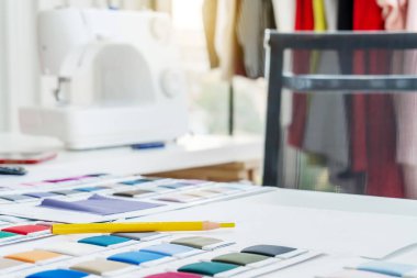 Yeni moda koleksiyonu oluşturuluyor. Giysilerin el çizimleri, ekrandaki renk örnekleri ve ahşap masa üzerindeki iplikler, yaratıcılık, terzilik ve tasarım konsepti