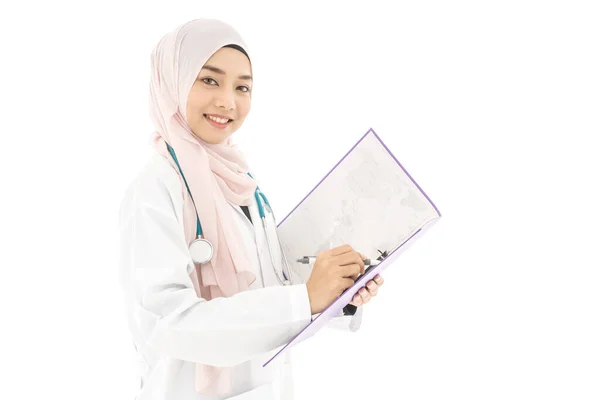 笑顔の肖像画美しい若いイスラム教徒の女性医師を着て医師の制服とヒジャブとステスコープ彼女のノートブックに書いて 白い背景に隔離された立って — ストック写真