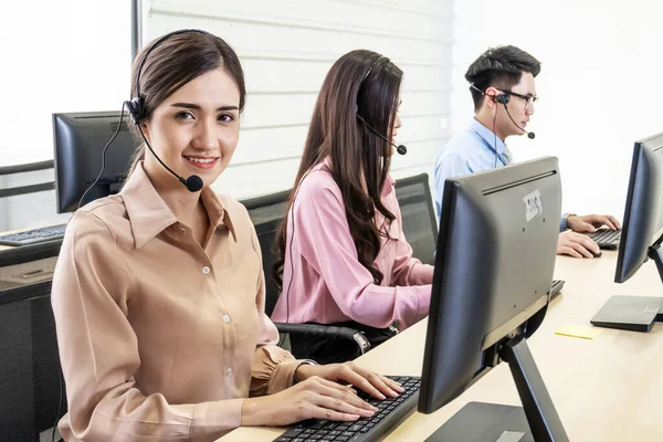 Call center, Service desk consultant talking on hands-free phone, Happy young female customer support executive working in office, Office and business concept