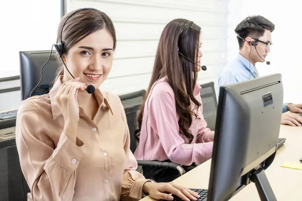 Call center, Service desk consultant talking on hands-free phone, Happy young female customer support executive working in office, Office and business concept