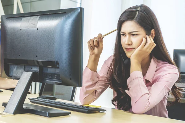 Çağrı merkezi, servis masası danışmanı telefonla konuşuyor çağrı merkezinden genç bayan operatör düşünüyor ve araştırıyor.
