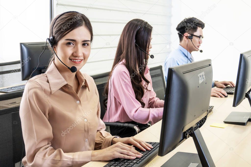 Call center, Service desk consultant talking on hands-free phone, Happy young female customer support executive working in office, Office and business concept