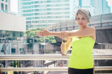 Fitness. Sokak Şehri 'nde egzersiz yapan kadın. Spor aletleriyle şık vücutlu güzel bir kız. Açık havada kollarını açarken müzik dinliyor. şehir biçimi.