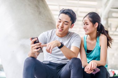 Akıllı telefonlu genç çiftler modern iç köprü inşaatında çalıştıktan sonra konuşuyorlar ve dinlenirken gülümsüyorlar..