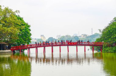 HANOI, VIETNAM - 13 Nisan 2013: Hoan Kiem Gölü 'ndeki Huc Köprüsü veya Güneş Köprüsü, kıyı şeridini Hoan Kiemmeer' daki Den Ngoc Oğlu adasına bağlayan kırmızı ahşap bir köprüdür.
