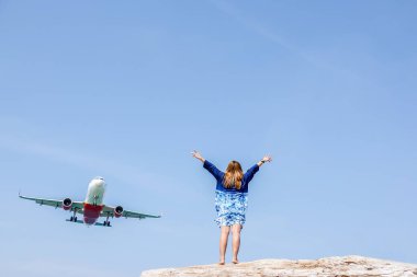 Görünmeyen Phuket, Phuket Uluslararası Havaalanı 'na iniş yapan uçakları izlemek için kumsal, güzel mutlu bir kadın ve uçan bir uçak, Tayland' da ada Phuket. Etkileyici bir cennet. Sıcak sahil Mai Khao.