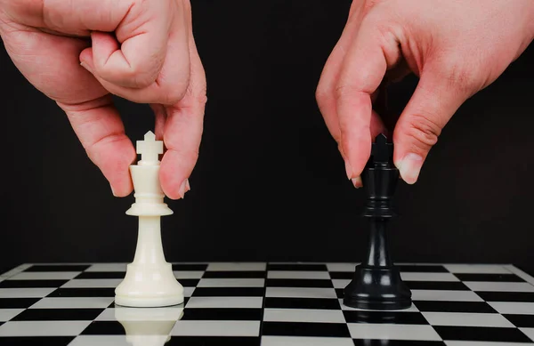 Business competition strategy and business success concept. Hand of two businessman moving for fighting dark king chess piece on chessboard game, business victory or decision the path to success.