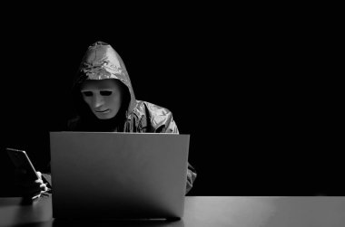 Beyaz maskeli ve kapüşonlu isimsiz bilgisayar korsanı. Karanlık yüz akıllı telefondan insanlara saldırıyor. Daha fazla para, veri hırsızı, internet saldırısı, darknet ve siber güvenlik konsepti ile kurbanla iletişime geçmek.