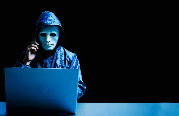 Beyaz maskeli ve kapüşonlu isimsiz bilgisayar korsanı. Siber saldırı için dizüstü bilgisayar kullanan ve cep telefonu, veri hırsızı, internet saldırısı, darknet ve siber güvenlik kavramını kullanan karanlık yüz..