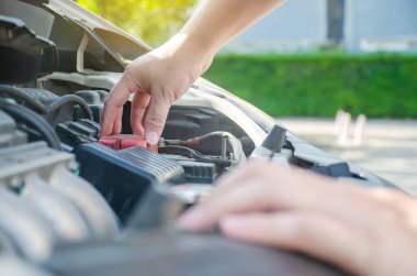 Bir adam arabanın motorunu kontrol ediyor, aküsünü tek başına kontrol ediyor..