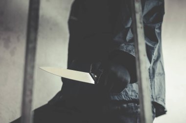Ganimet için elinde bıçakla merdivenlerde yürüyen maskeli bir haydut.