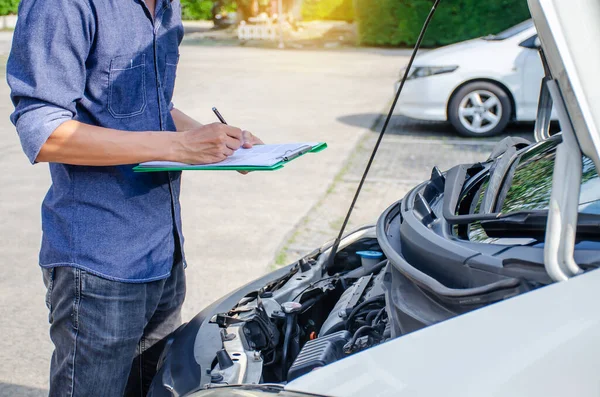 Asyalı erkek mühendisler ve teknisyenler panoya yazı yazıyor ve mekanik araba motoru, servis ve bakım arabası veya aracı kontrol ediyorlar..