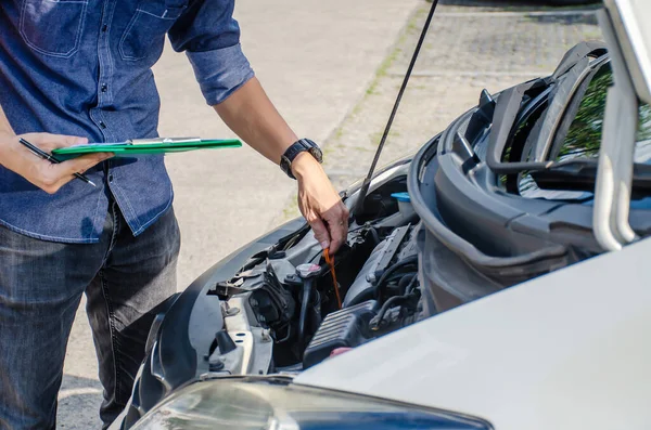 Otomobil tamircisi araba motorundaki yağ seviyesini kontrol ediyor, dipstick kullanıyor, arabadaki yağ seviyesini kontrol ediyor ve bakımı yapıyor..