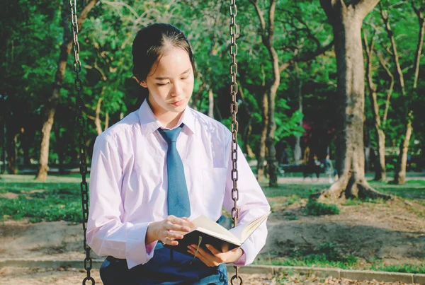 Piękna Nastolatka Szkolnym Mundurze Czytając Książkę Podczas Siedzenia Huśtawce Parku — Zdjęcie stockowe