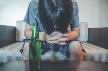 Yalnız ve çaresiz, alkol bağımlısı bir adam. El ele tutuşun, yalnızlık ve bağımlılık kavramı, seçici odak şişesi.