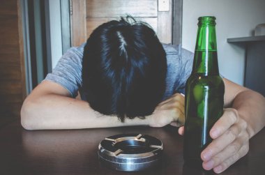 Yalnız ve çaresiz, alkol bağımlısı bir adam masada uyuyor. Üzgün erkek yetişkin alkol sorunu yaşıyor, seçici odak şişesi