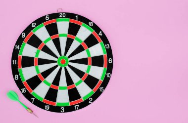 Yeşil dart oku ve dart tahtası, pembe renkli arka planda. Düz yatıyordu. Boşluğu kopyala