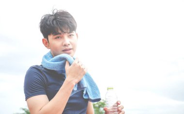 Yorgun koşucu dışarıda stadyumda spor yaptıktan sonra terini havluyla siliyor.