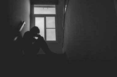 Siluet Üzgün genç adam karanlıkta merdivenlerde oturuyor, depresyon ve endişe bozukluğu konsepti, yaşam sorunları, hastalık, üzüntü, umutsuzluk, karanlık.