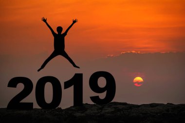 Genç adamın silueti mutlu atlamalar 2019 yılına kadar gökyüzü ve güneş ışığı arkaplanı. metin için boşluk kopyala. Gelecek ve zaman geçişi kavramı.
