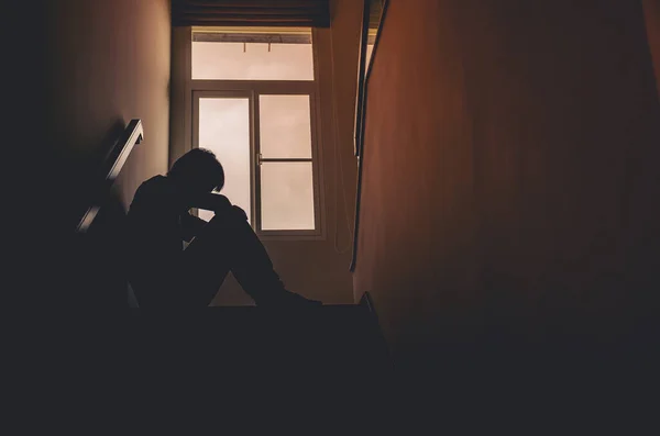 シルエット悲しい若い男が暗闇の中で階段に座って うつ病や不安障害の概念 人生の問題 悲しみ — ストック写真
