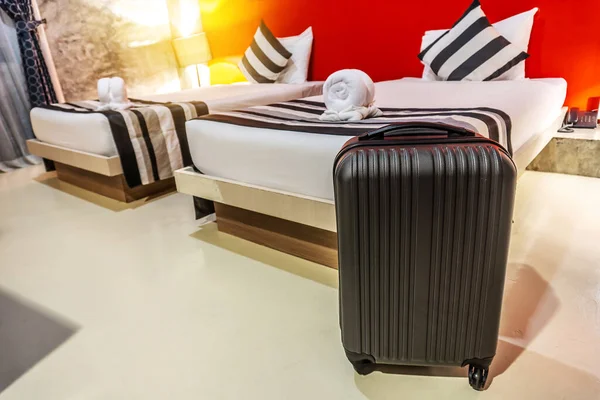 Single black plastic hard shell luggage with extended telescopic handle in the hotel room, One suitcase prepared for business trip. Traveling alone concept. copy space for text