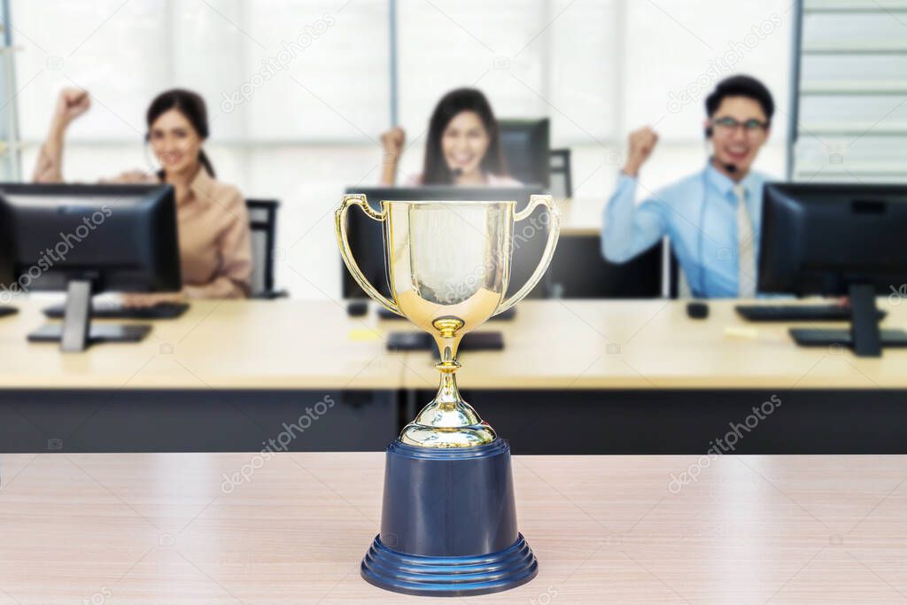 Close up of a trophy in front of a working business people, achieve business concept.